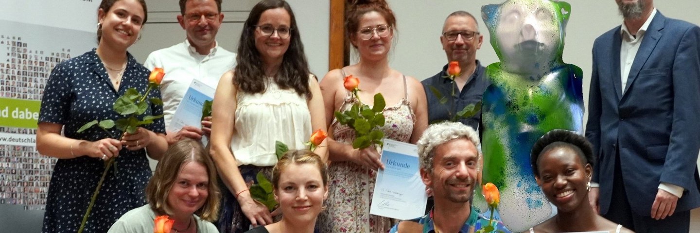 Gruppenbild zeigt verschiedene Personen auf einem Podium im Audimax